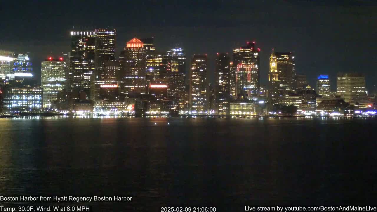 A nighttime view of a city skyline across a dark body of water, with a temperature of 30°F and a west wind of 8 mph.