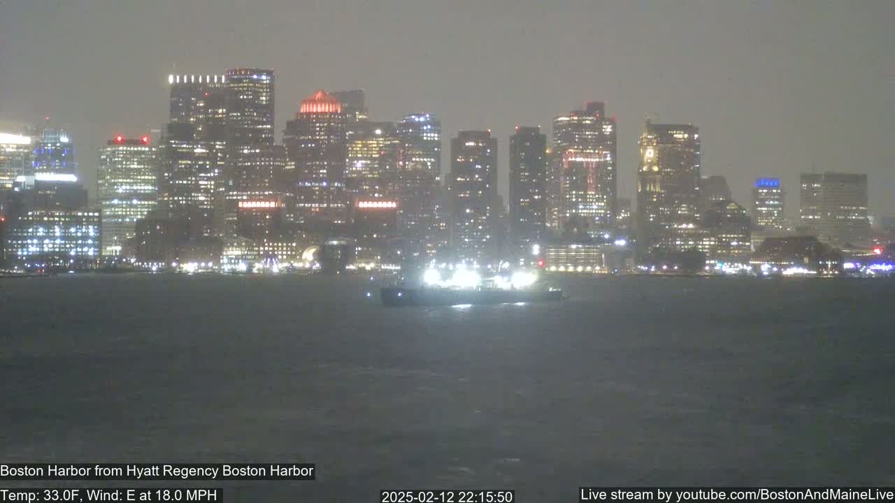 A nighttime view of a city skyline across a choppy harbor in foggy or hazy conditions.