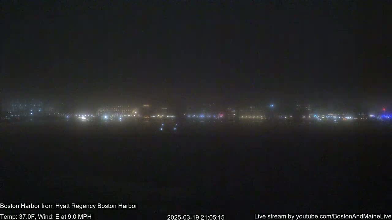 A hazy, nighttime view of a city skyline across a body of water, with an easterly wind at 9 mph and a temperature of 37°F.