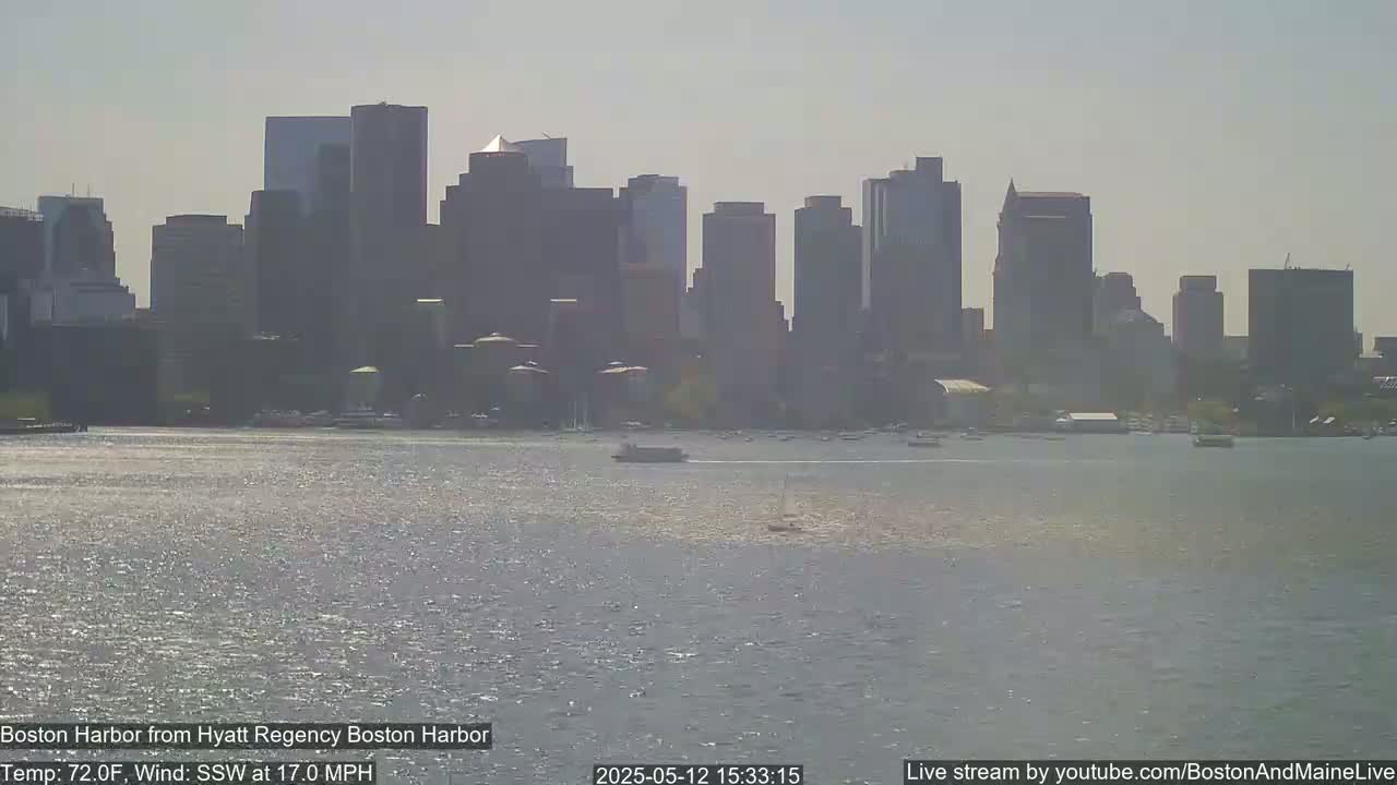 A hazy view of the Boston skyline across a choppy harbor on a sunny 72°F day with a 17 mph south-southwest wind.