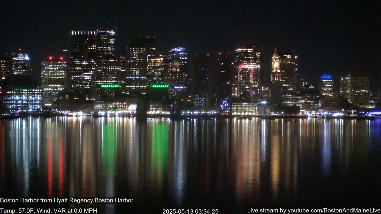 A brightly lit city skyline at night is reflected in a calm body of water.