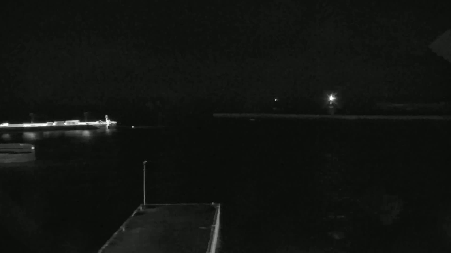 A nighttime view of a dark body of water with a ship and lights on the opposite shore.