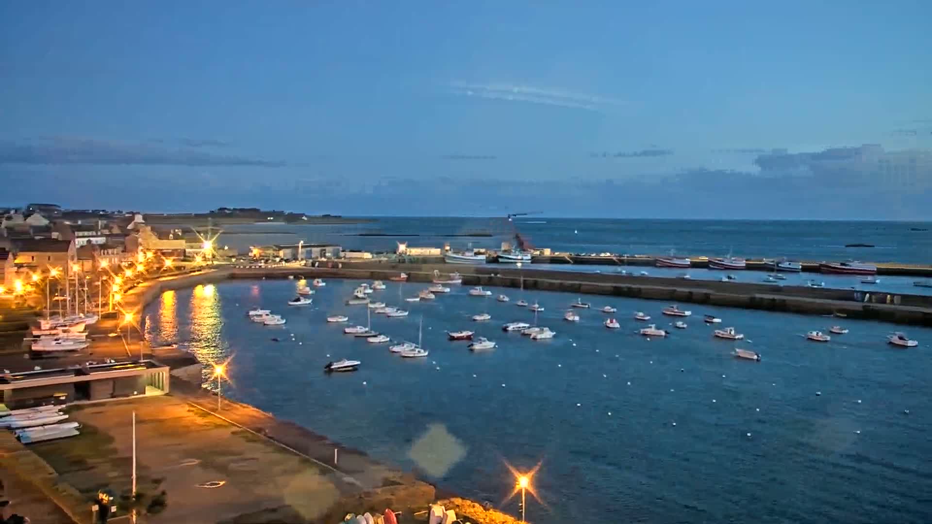 A harbor filled with numerous boats at twilight under a clear sky.