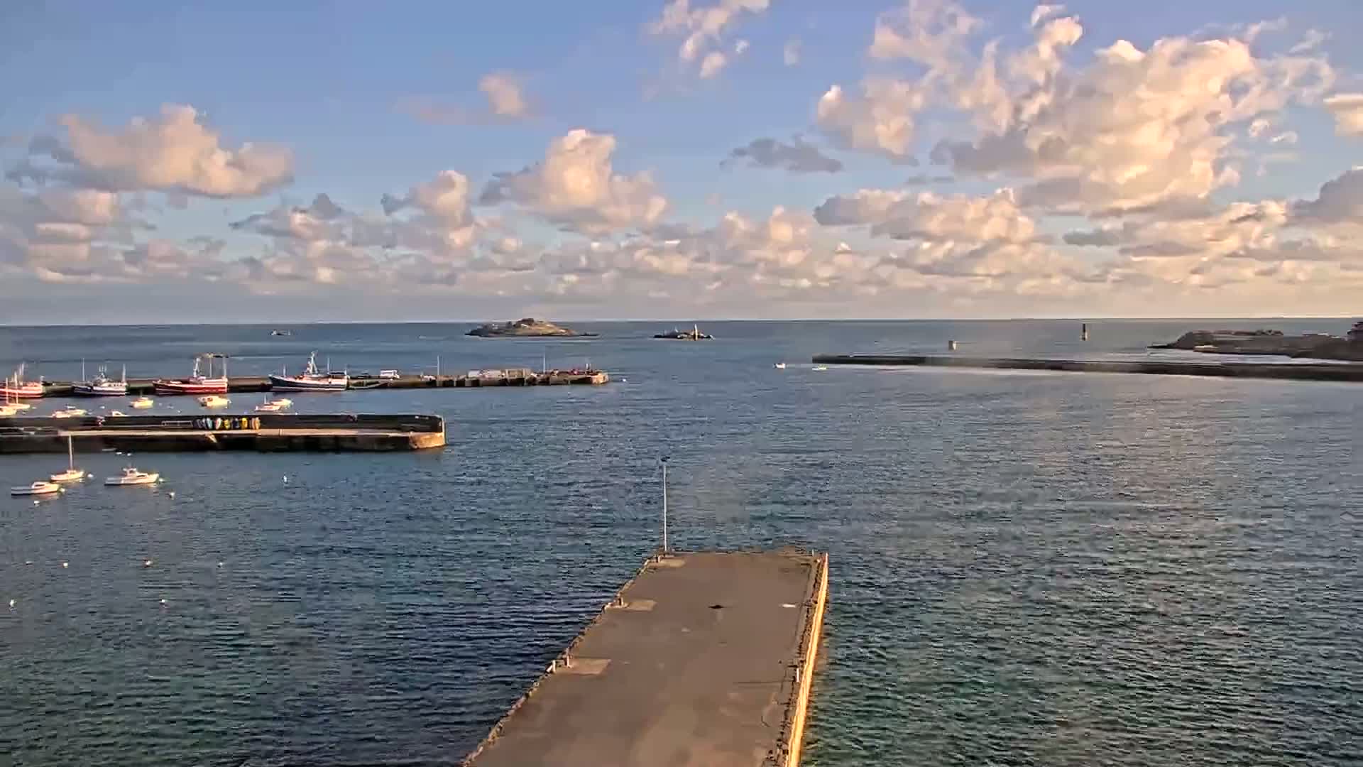 A harbor with several fishing boats docked under a partly cloudy sky.