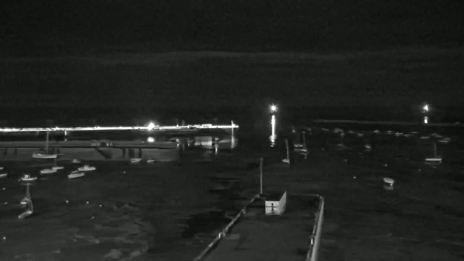 A nighttime view of a harbor filled with boats under a dark, clear sky.