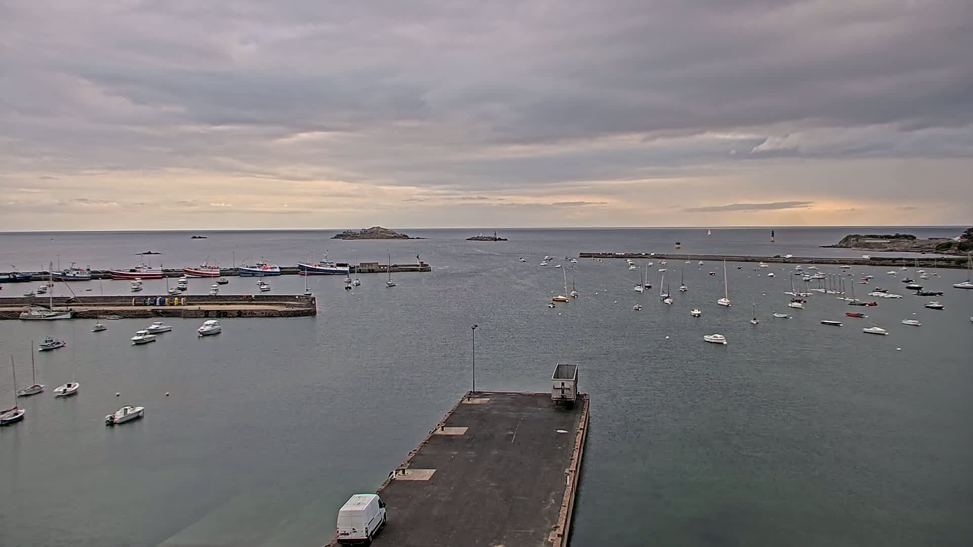 A harbor filled with numerous boats under an overcast sky, with a small island visible in the distance.