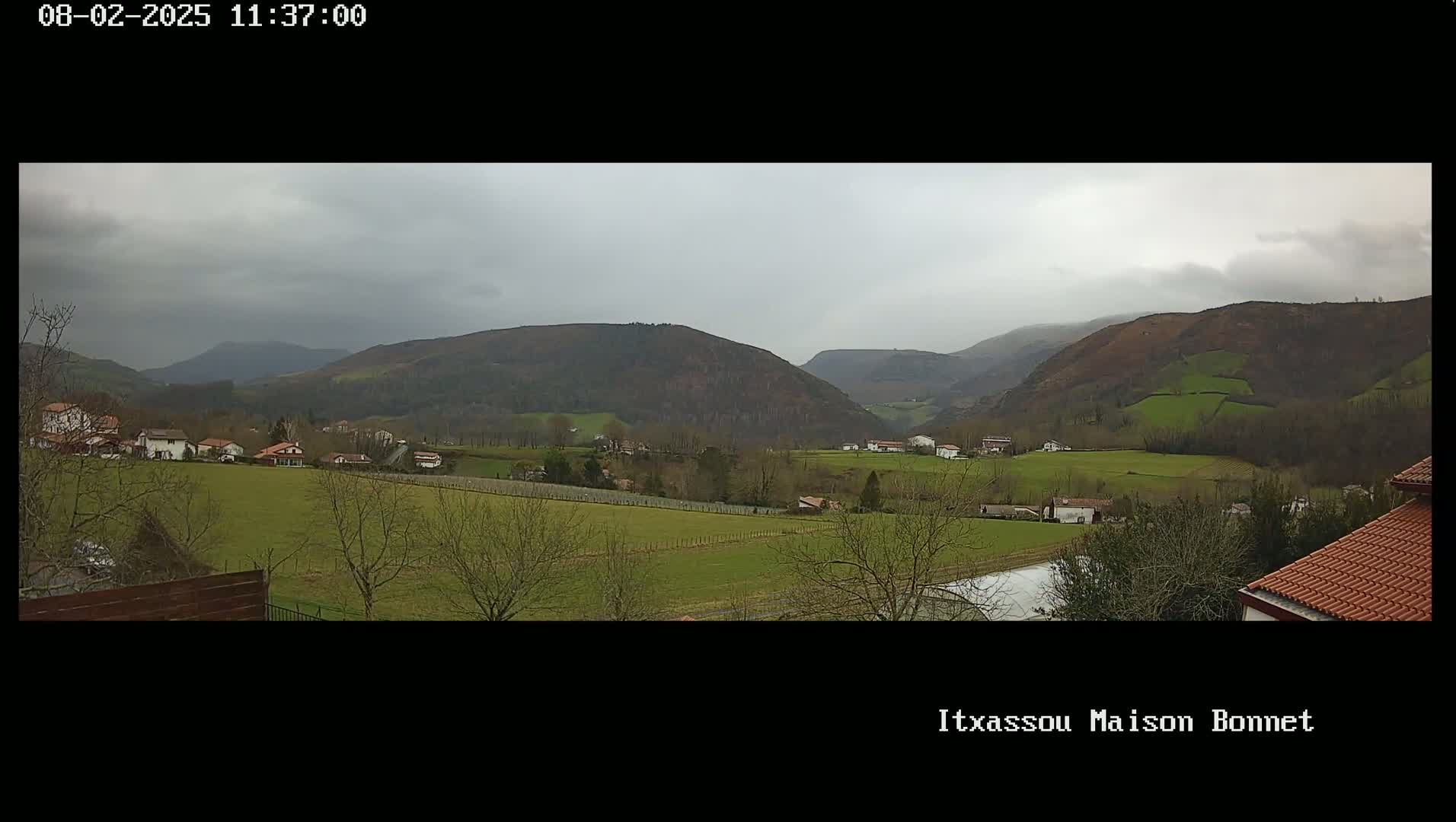 A sprawling green valley dotted with houses and farmland under an overcast sky.