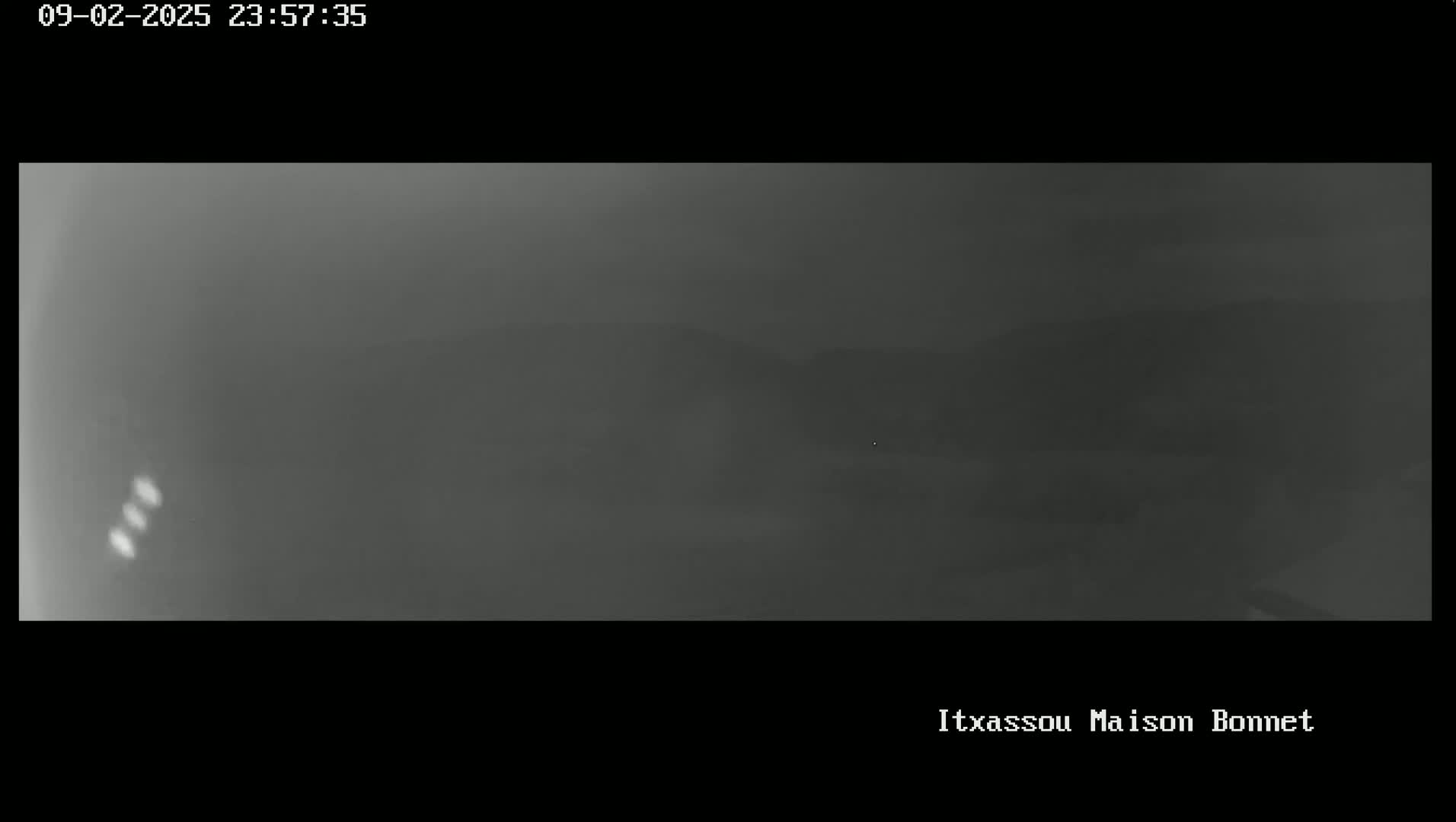 A nighttime, foggy view shows a dimly lit landscape.
