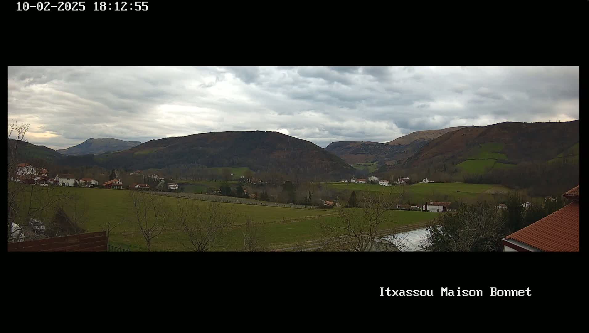 A sprawling valley dotted with houses and farmland under a cloudy sky.