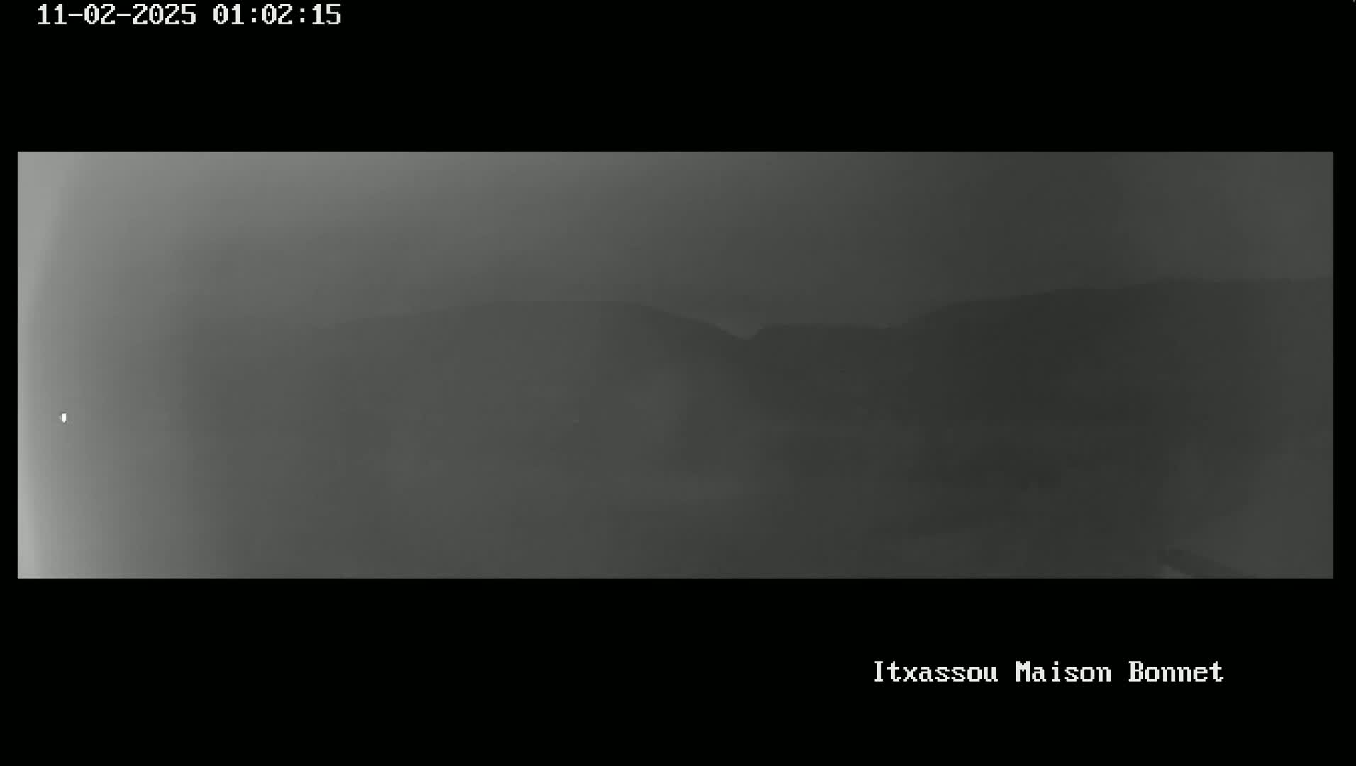 A foggy, dark grayscale view of distant hills is visible.