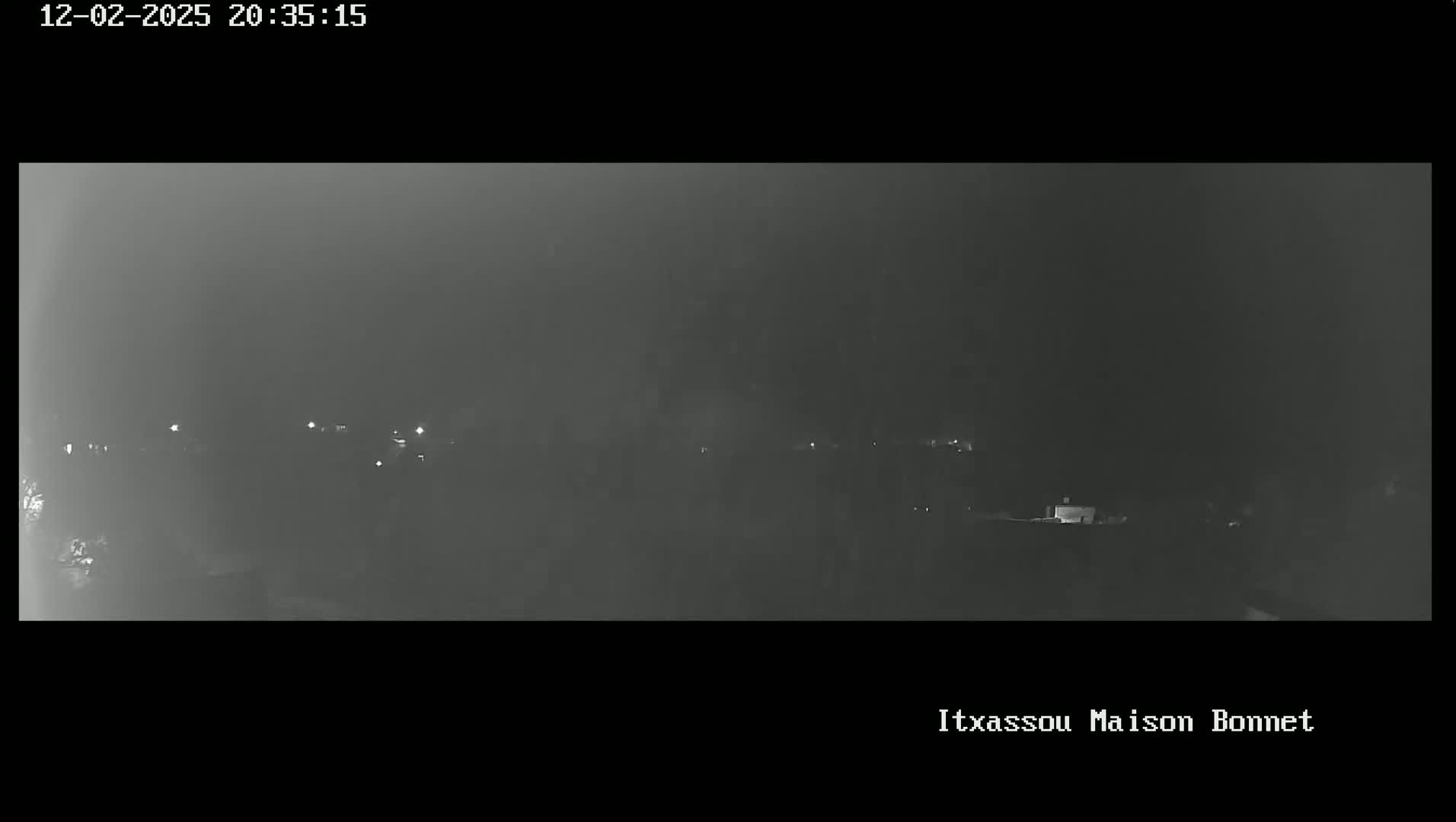 A hazy, nighttime view of a dimly lit landscape with a few scattered lights.