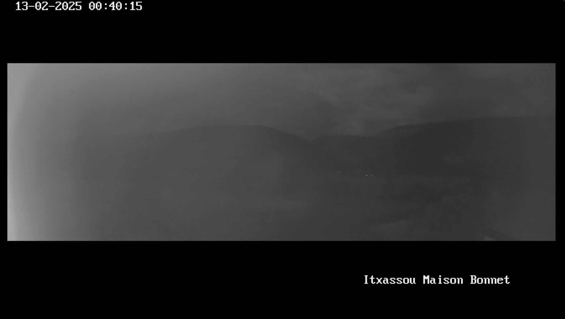 A hazy, dark gray landscape shows distant hills under a cloudy night sky.
