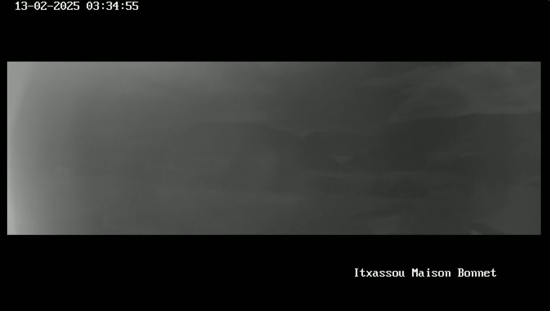 A blurry, dark gray image shows a foggy or hazy landscape with indistinct hills or mountains in the distance.