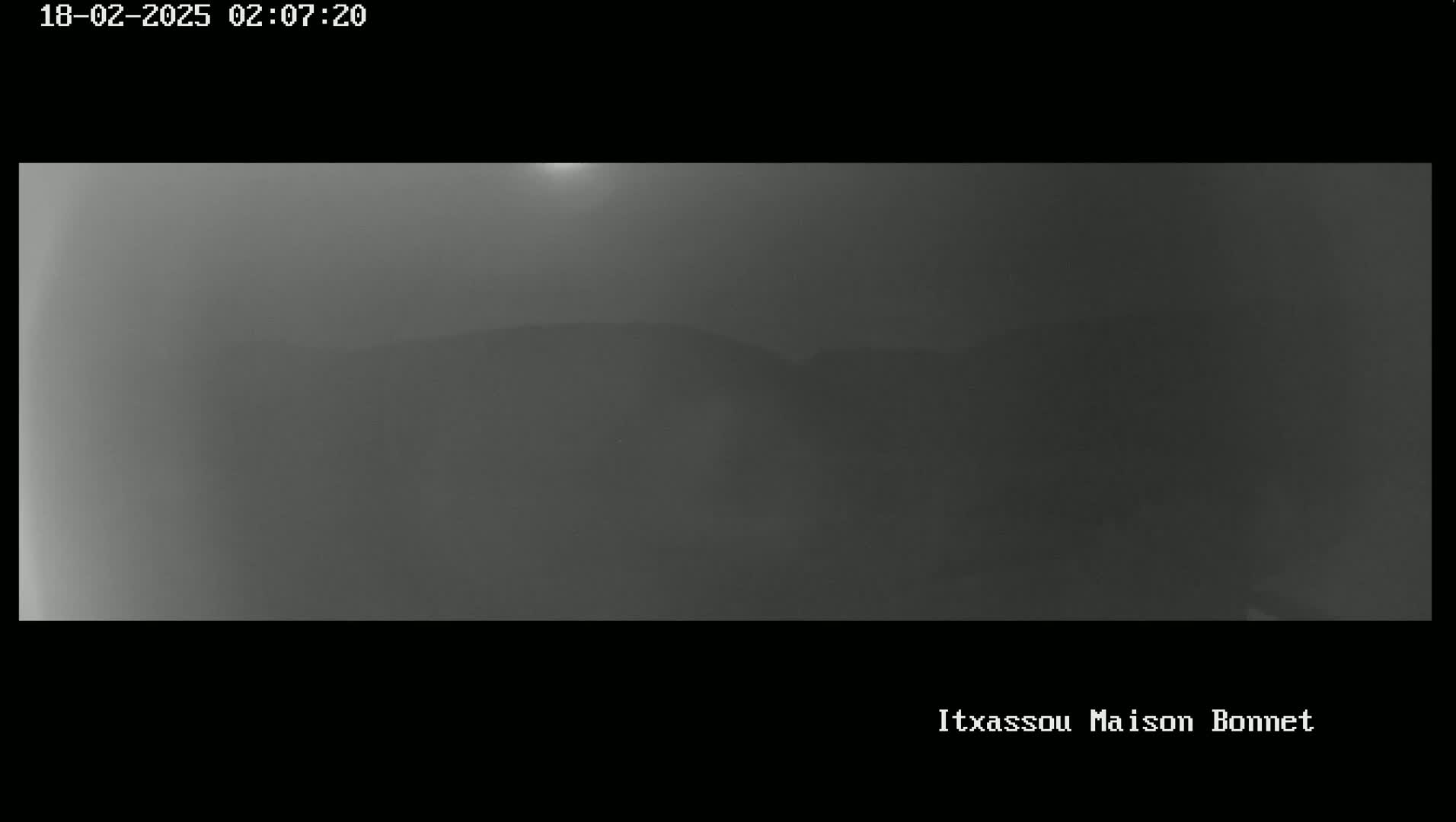 A hazy, gray landscape with a barely visible hill in the distance is shown under a dimly lit sky.