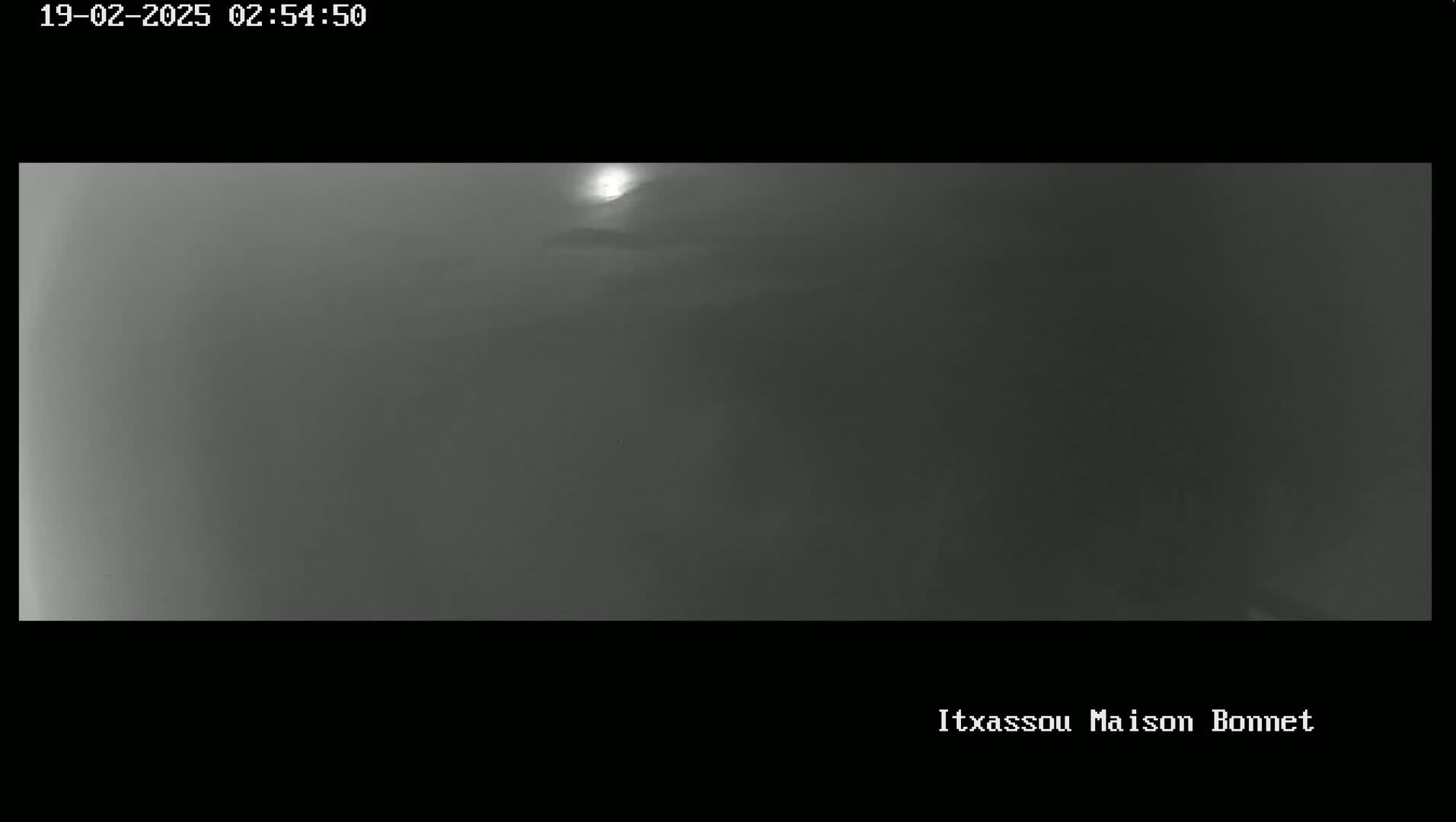 A hazy, dim outdoor scene shows a bright light, possibly the sun, partially obscured by clouds or fog.