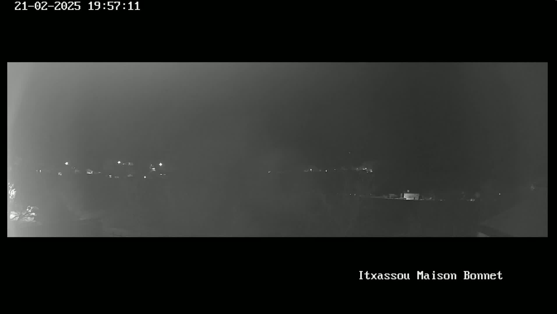 A hazy, nighttime view shows a distant line of dimly lit buildings.