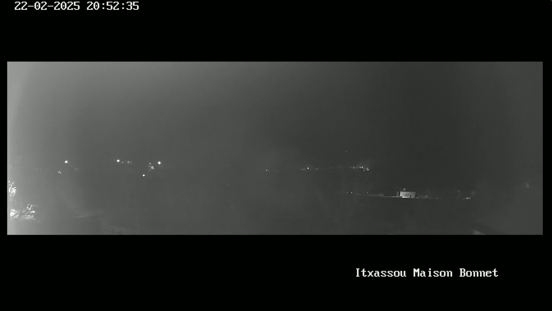 A nighttime, hazy view of a dimly lit landscape with a few scattered lights.