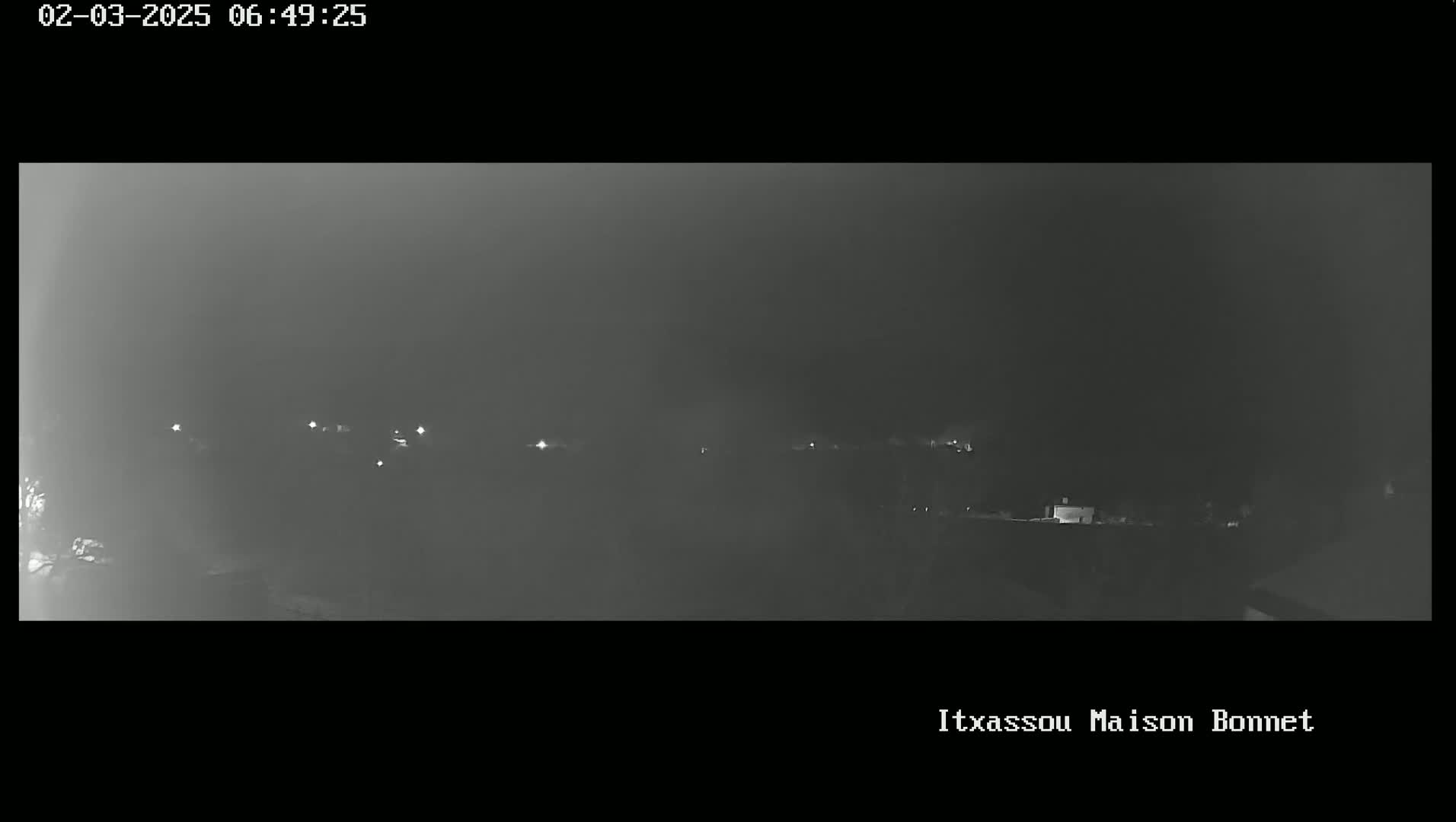A nighttime, hazy view of a dimly lit landscape with scattered lights.