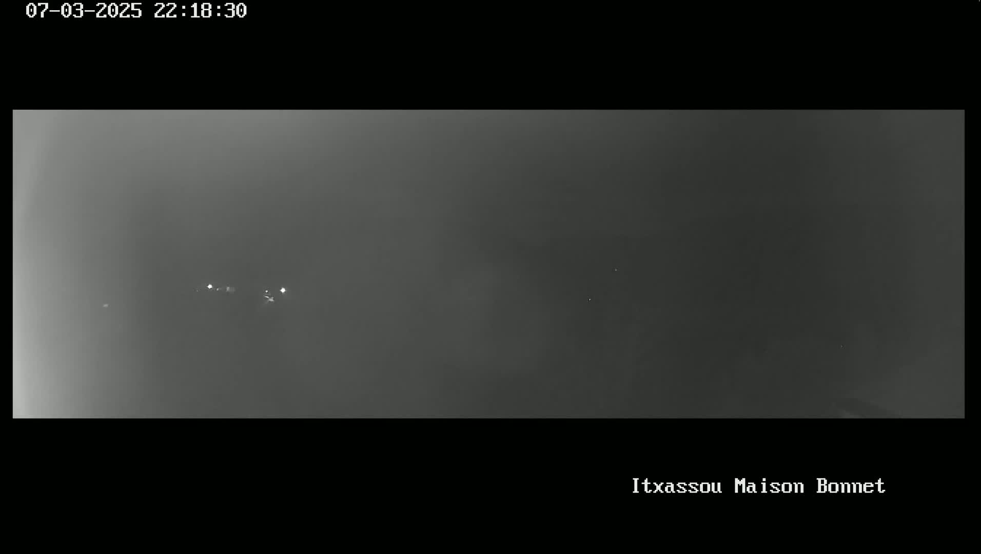 A nighttime, foggy scene shows a few distant lights.
