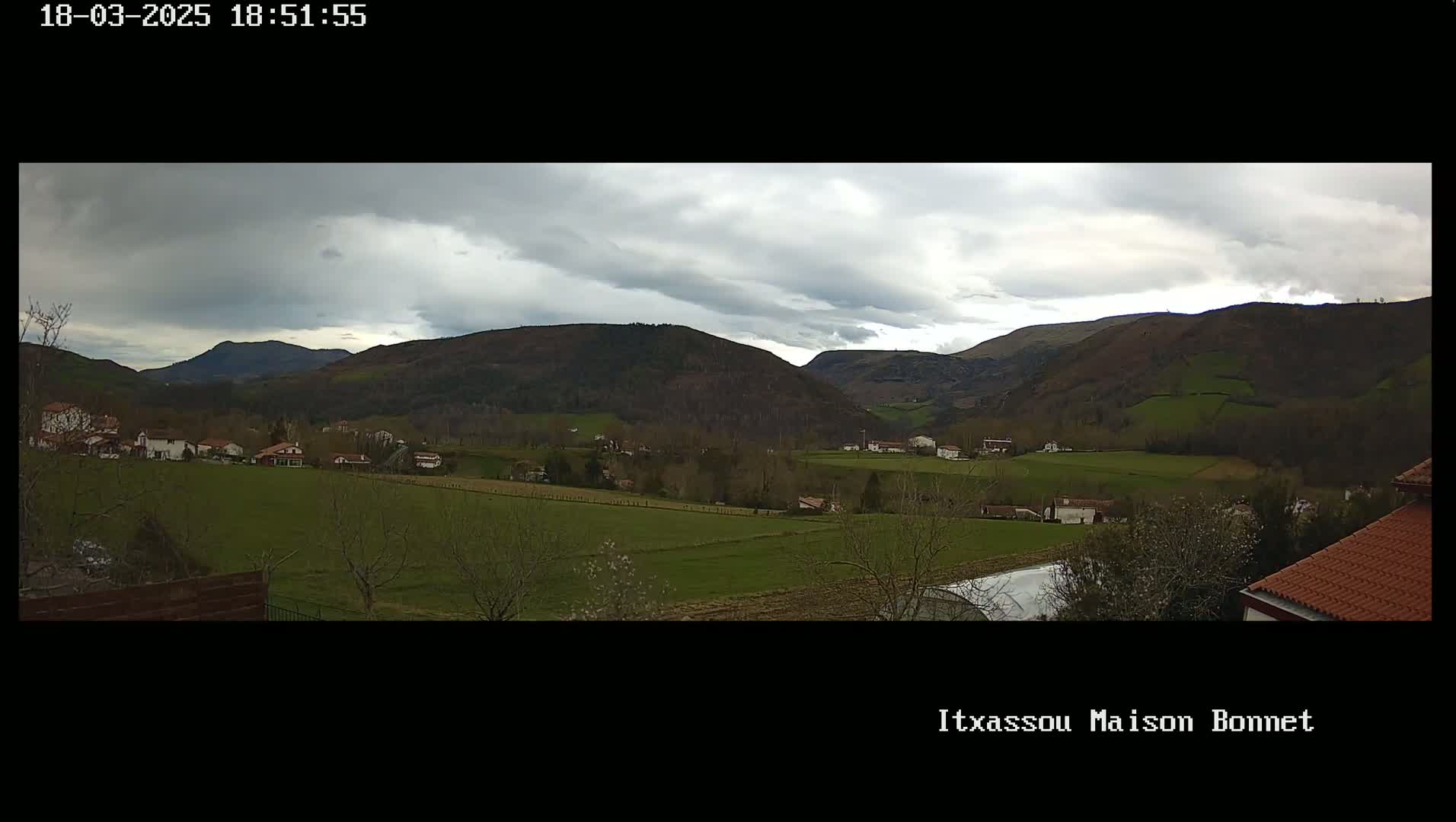 A sprawling valley dotted with houses and farmland under a cloudy sky.