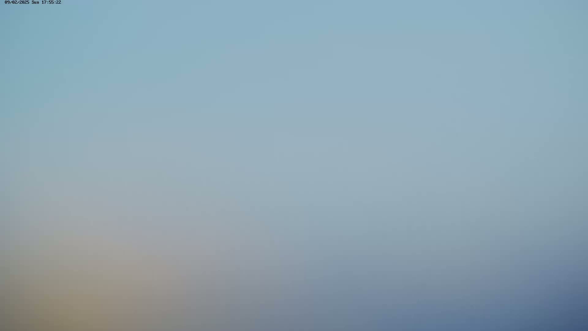 A hazy, light blue sky is visible, with a slightly lighter, yellowish hue near the bottom.