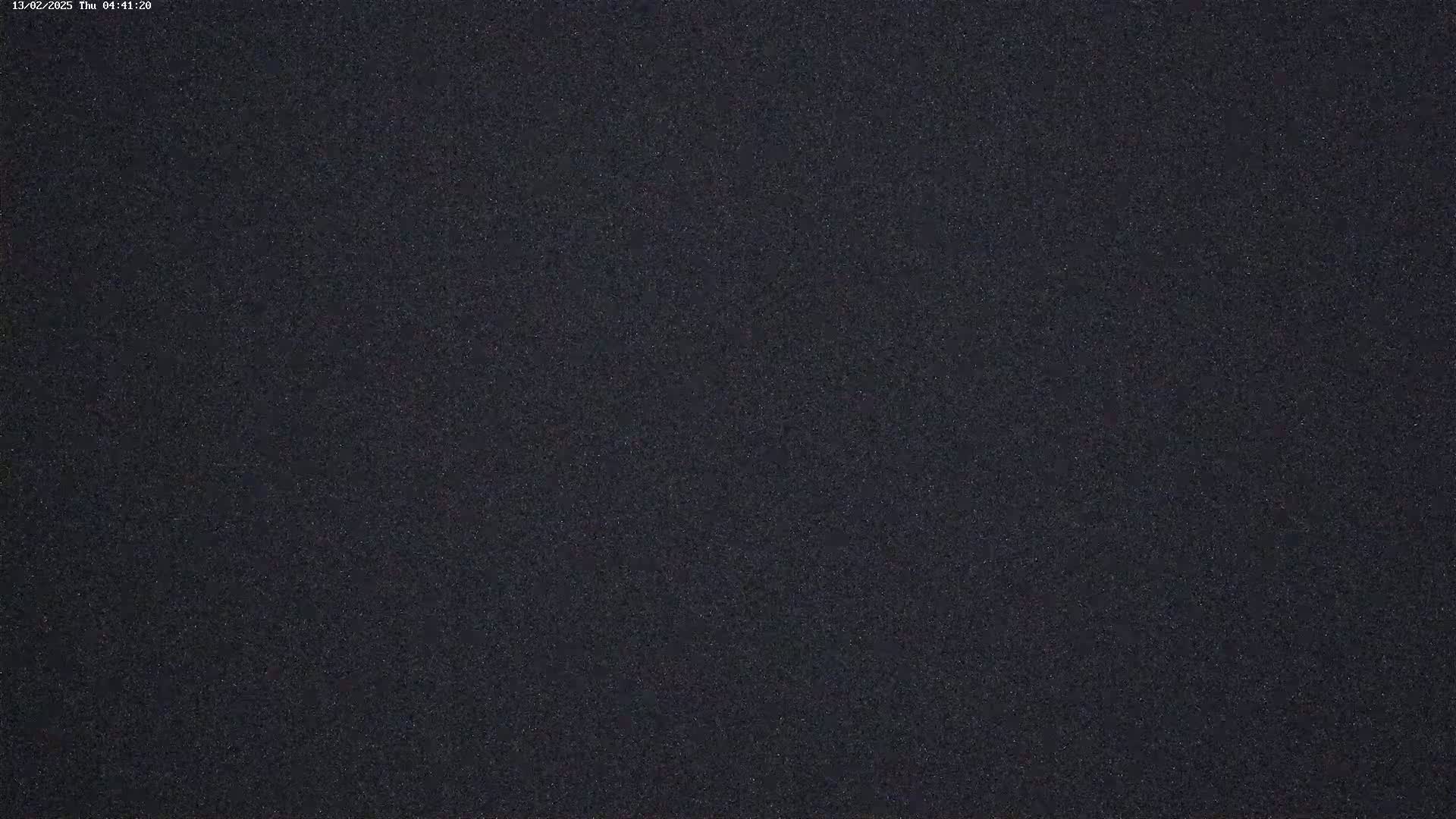 The image shows a dark, grainy texture, possibly a nighttime sky with faint stars.