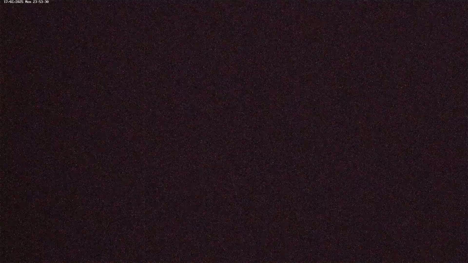 A dark, grainy image showing a night sky filled with stars.
