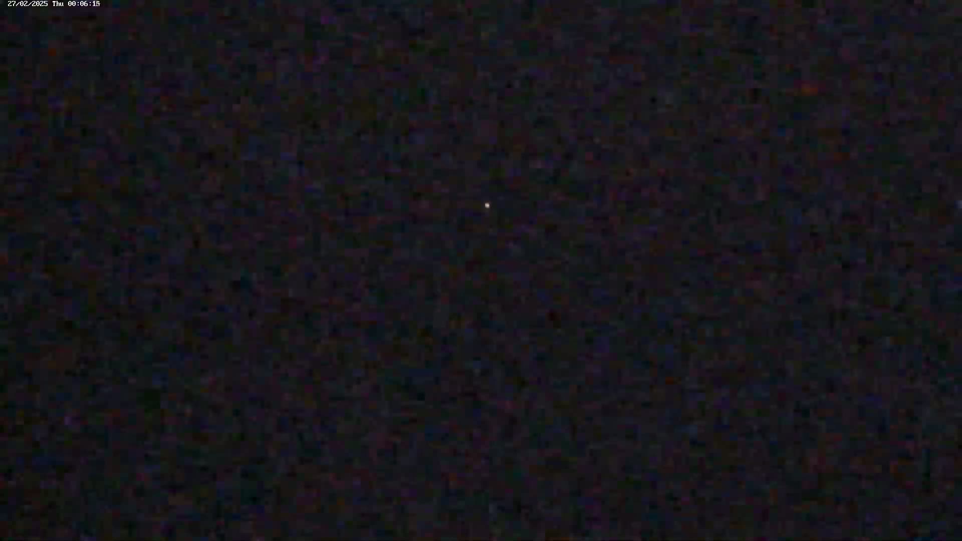 A single, faint light is visible in a dark, nighttime sky.
