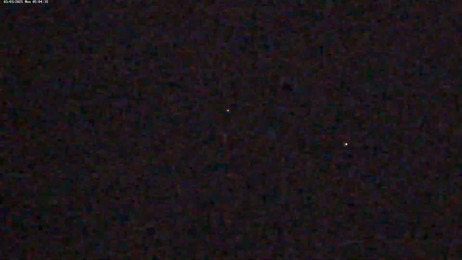 A dark, nighttime scene shows two faint, distant lights in a mostly dark sky.