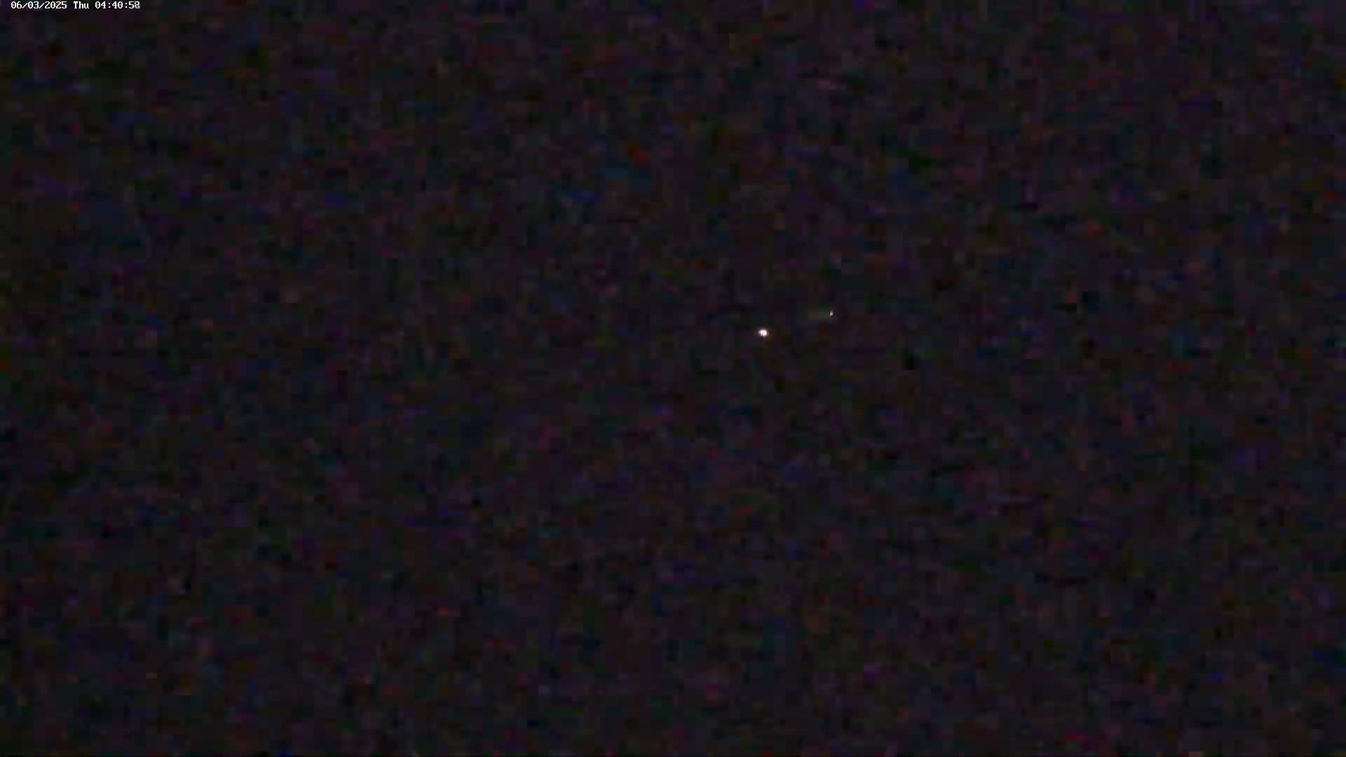 A single, faint light is visible in a dark, night sky.