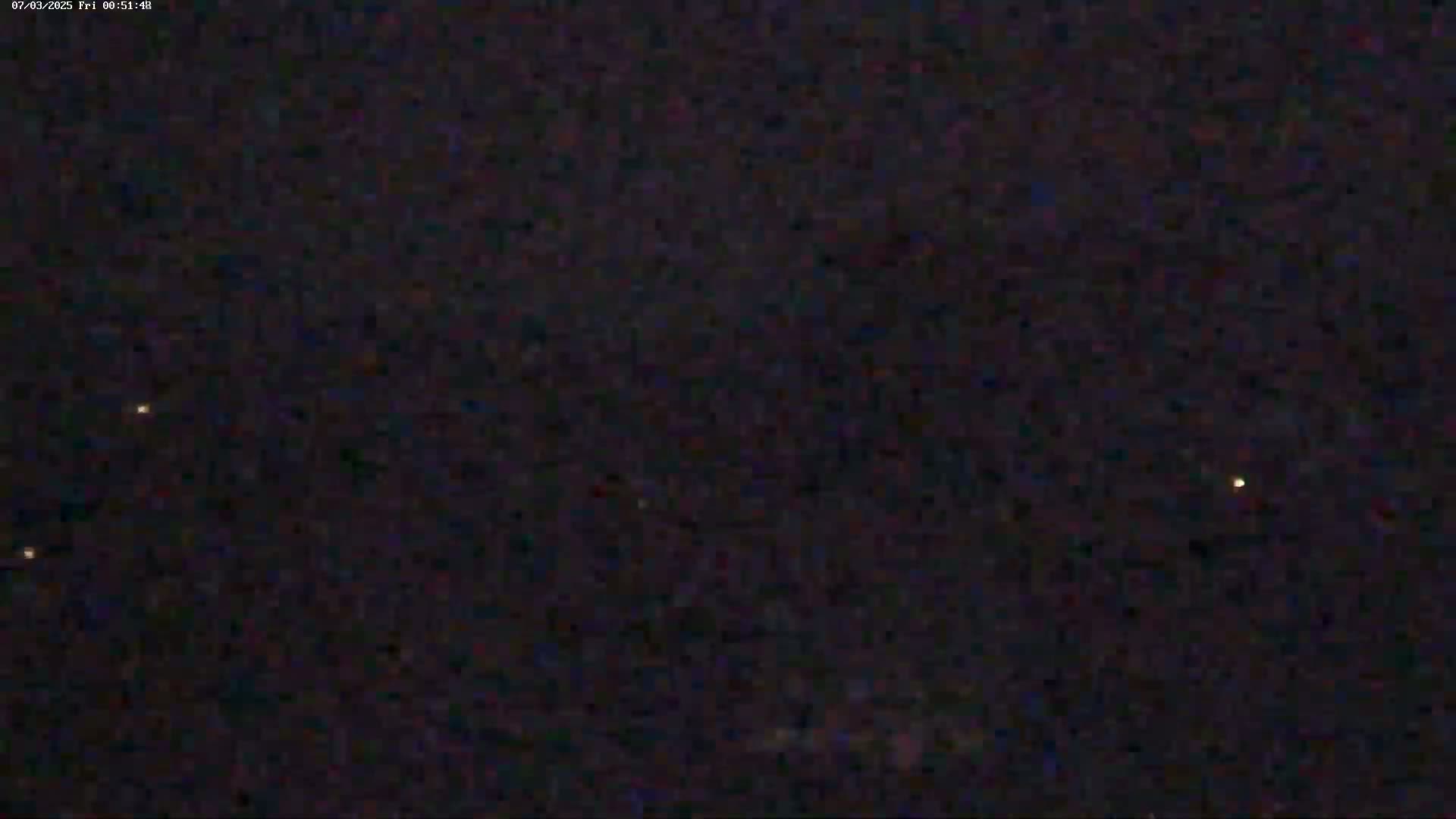 A night sky with several faint, distant lights visible against a dark background.