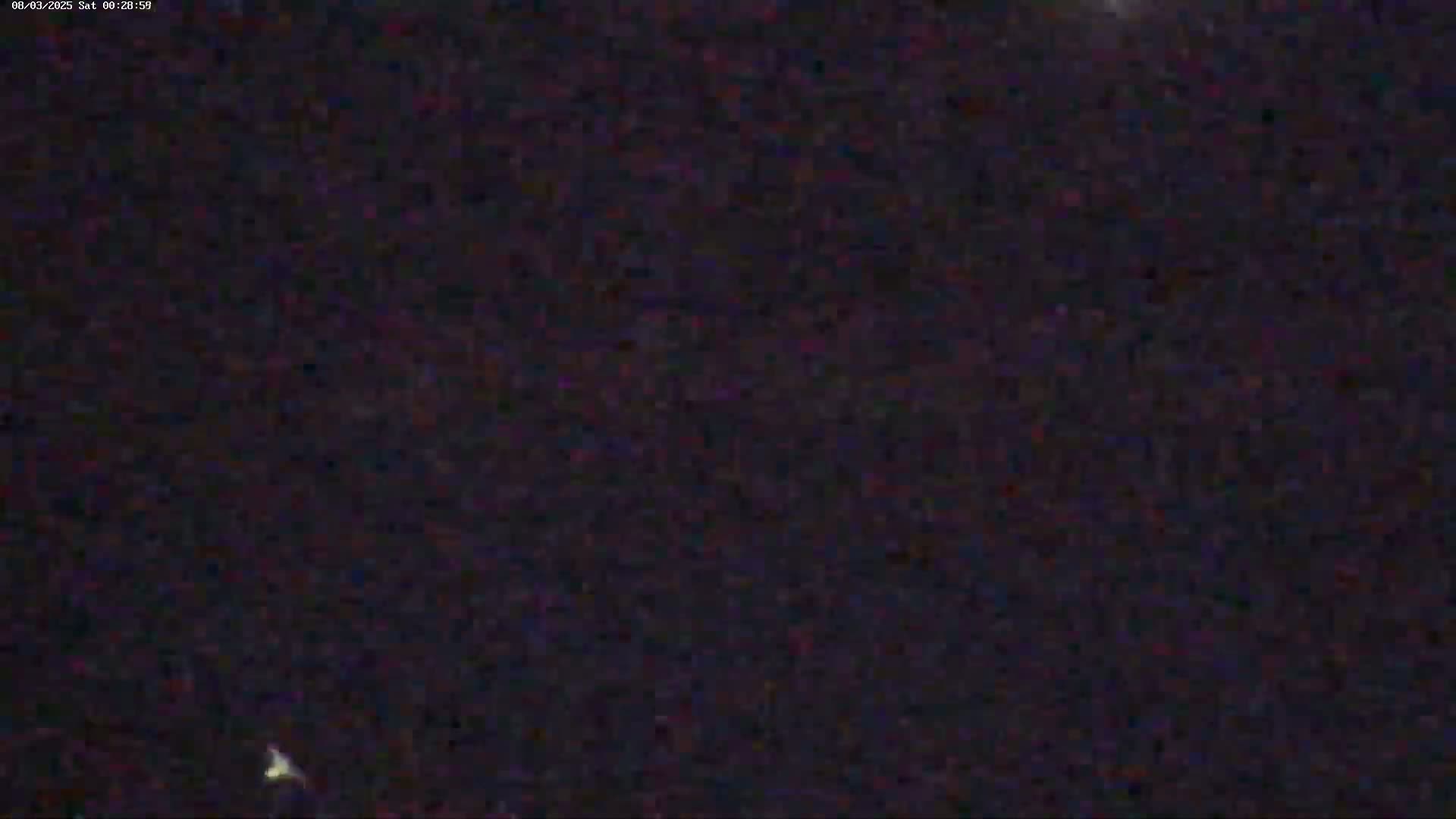 A dark, nighttime scene shows a mostly clear sky with a few faint, distant lights.
