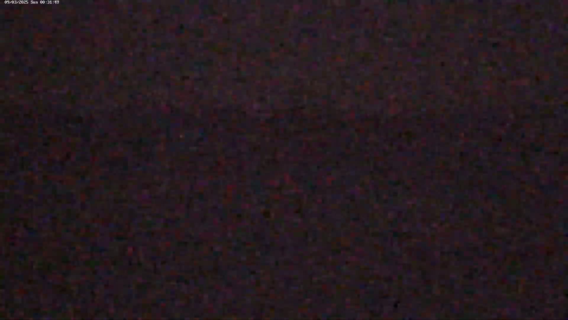 The image shows a dark, grainy, and blurry view, possibly of nighttime, with little to no discernible detail.