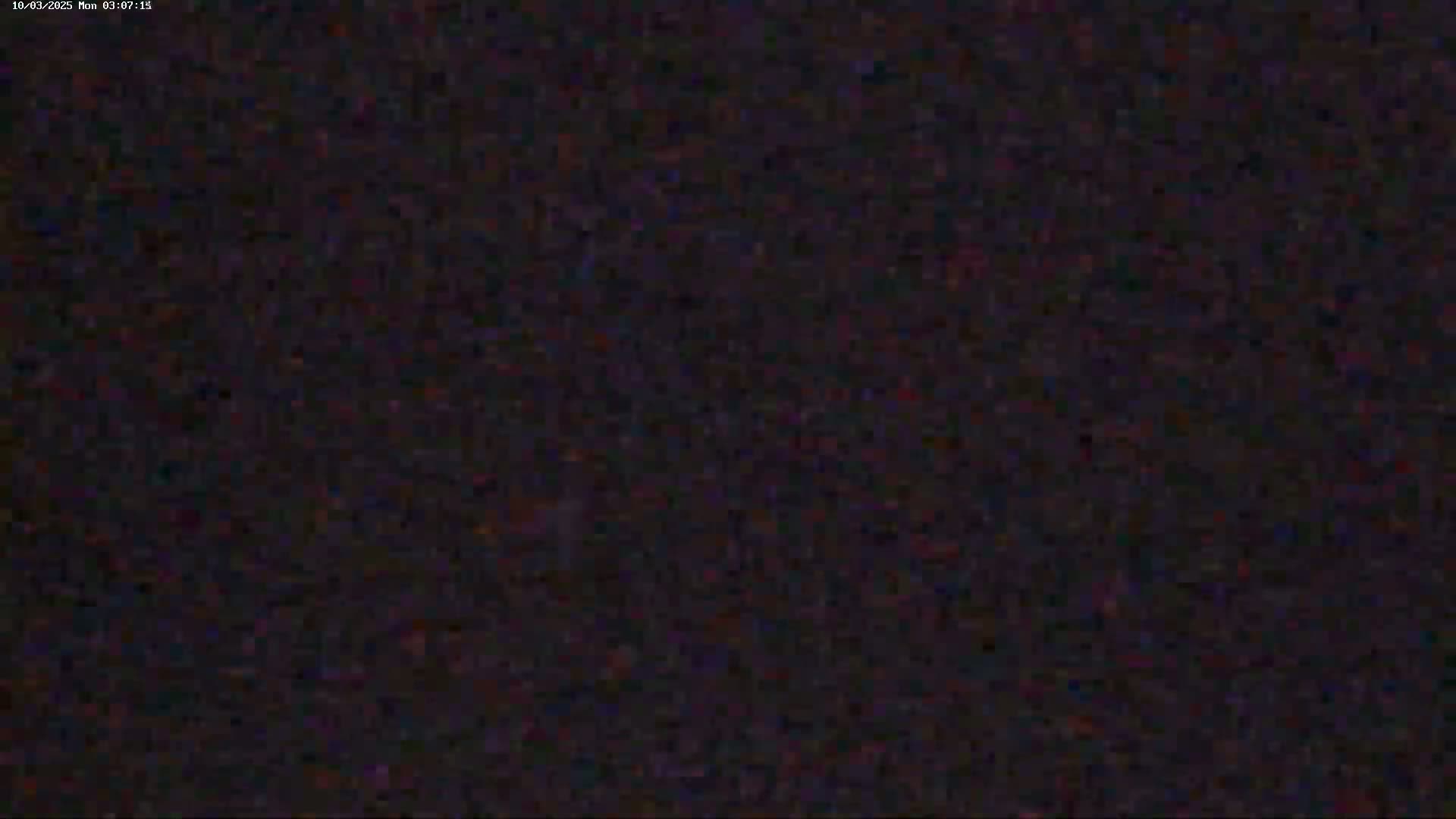 The image shows a dark, grainy, and indistinct view, possibly of a nighttime scene with poor visibility.