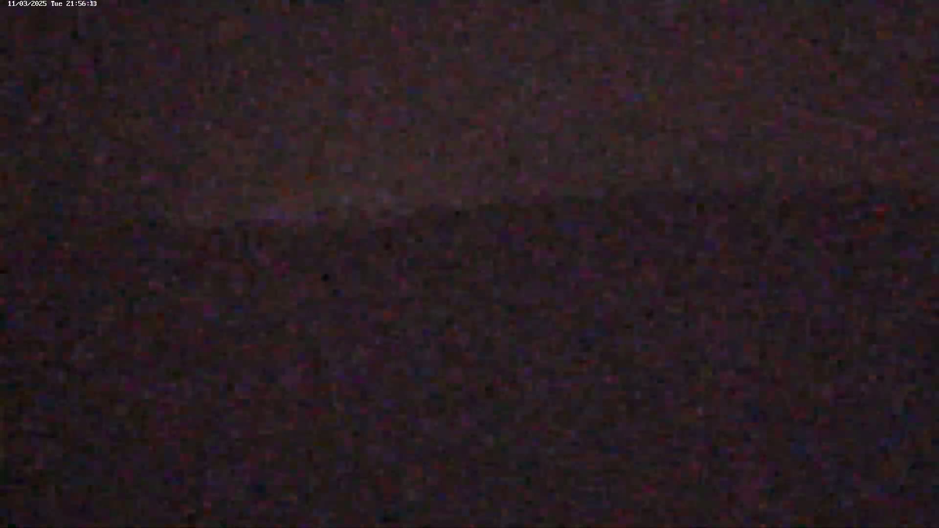 A dark, blurry image shows a nighttime landscape with a barely visible horizon line under a dark sky.
