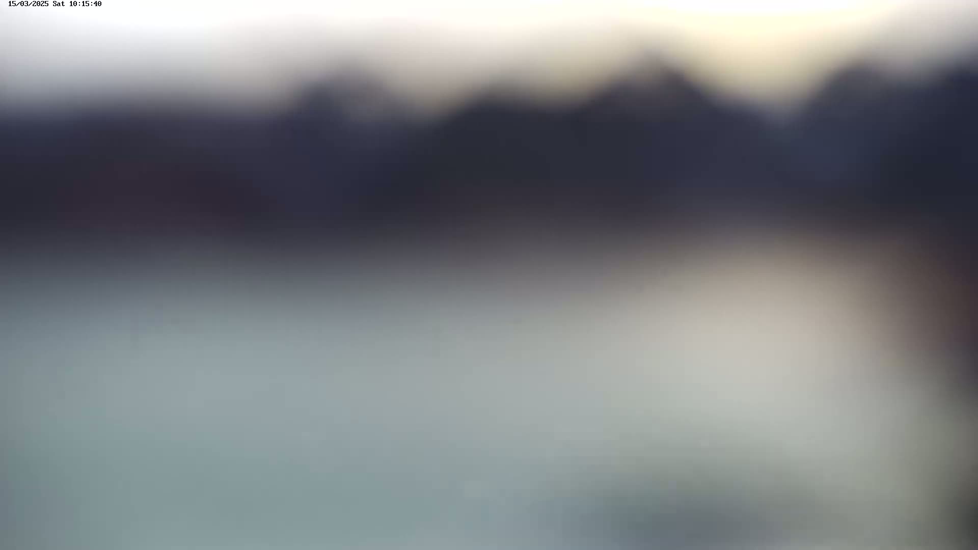 A blurry, out-of-focus image shows a dark, indistinct landscape under a hazy, light sky.