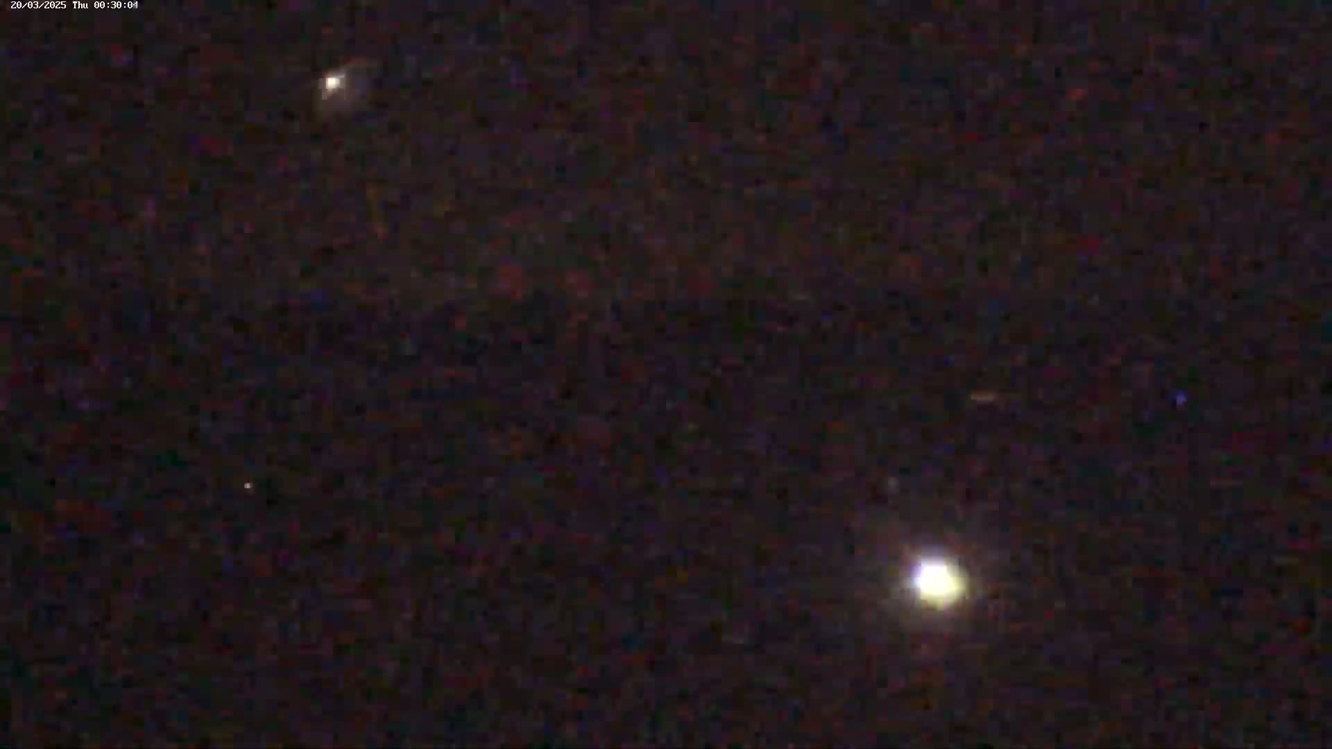 A night sky shows several bright lights, possibly stars or planets, against a dark background.