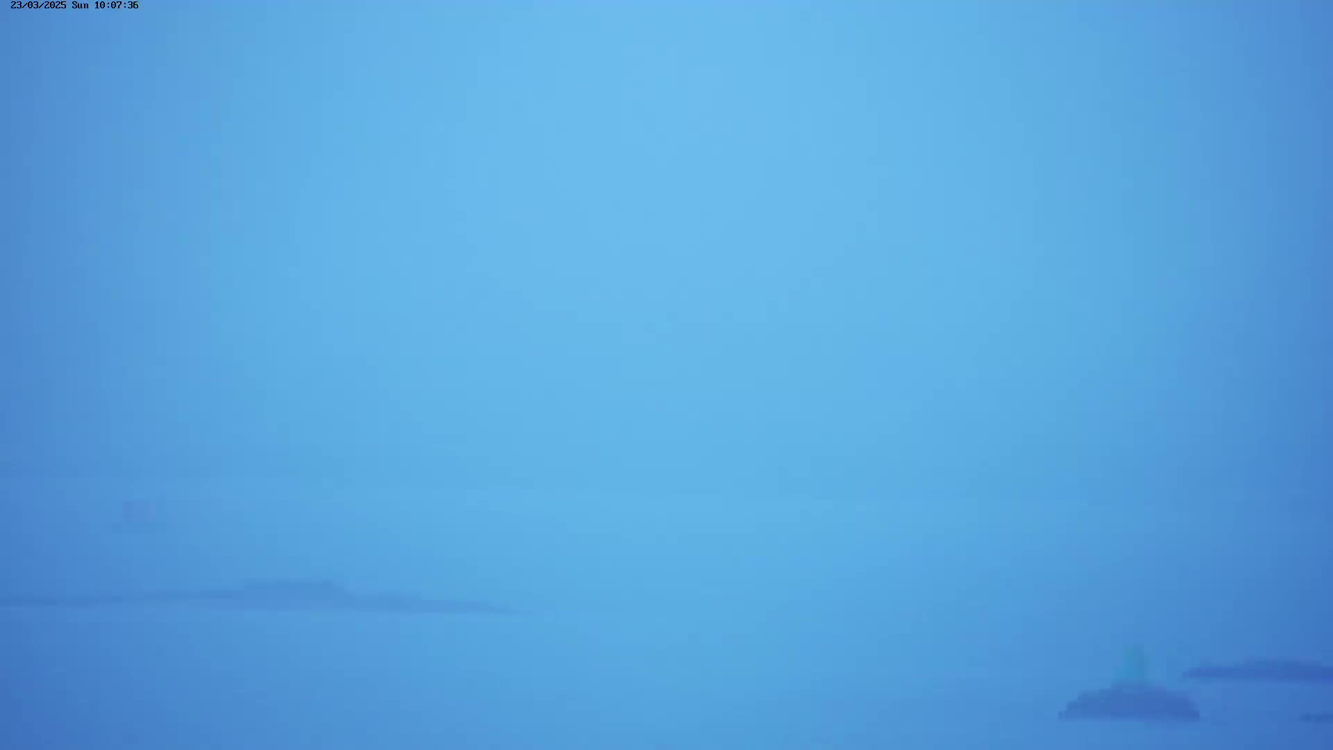 A hazy, light-blue landscape shows indistinct landmasses in the distance under a pale blue sky.