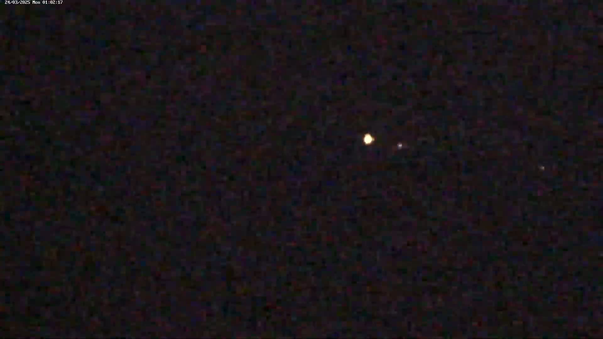 A nighttime image shows three faint, luminous points of light in the dark sky.