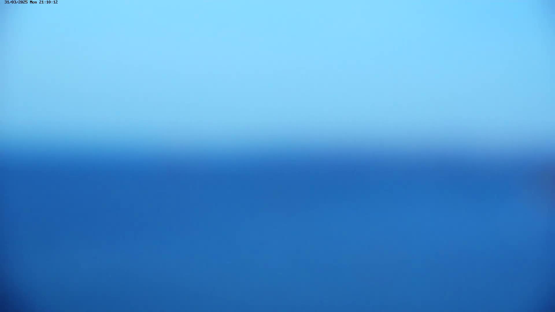 A blurry image shows a gradient of blue, transitioning from a lighter shade of blue at the top to a deeper blue at the bottom, suggesting a clear sky over calm water.