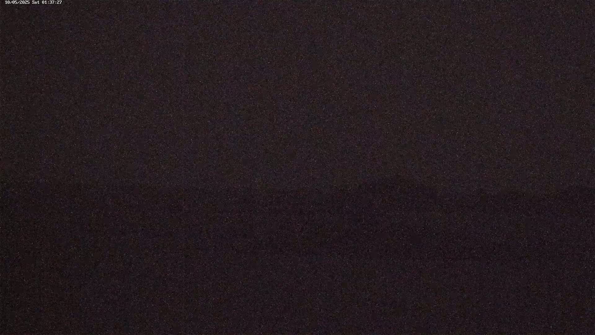 A dark, grainy image shows a mostly black surface with subtle variations in shade.