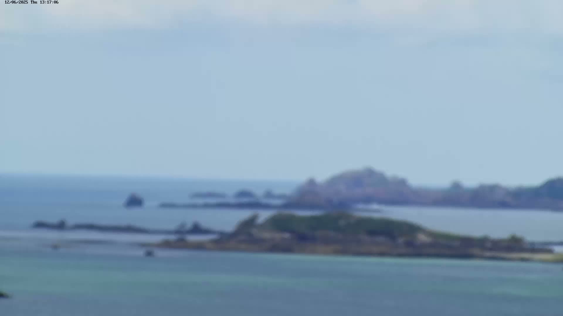 A blurry long shot shows a calm sea with several small islands under a hazy sky.