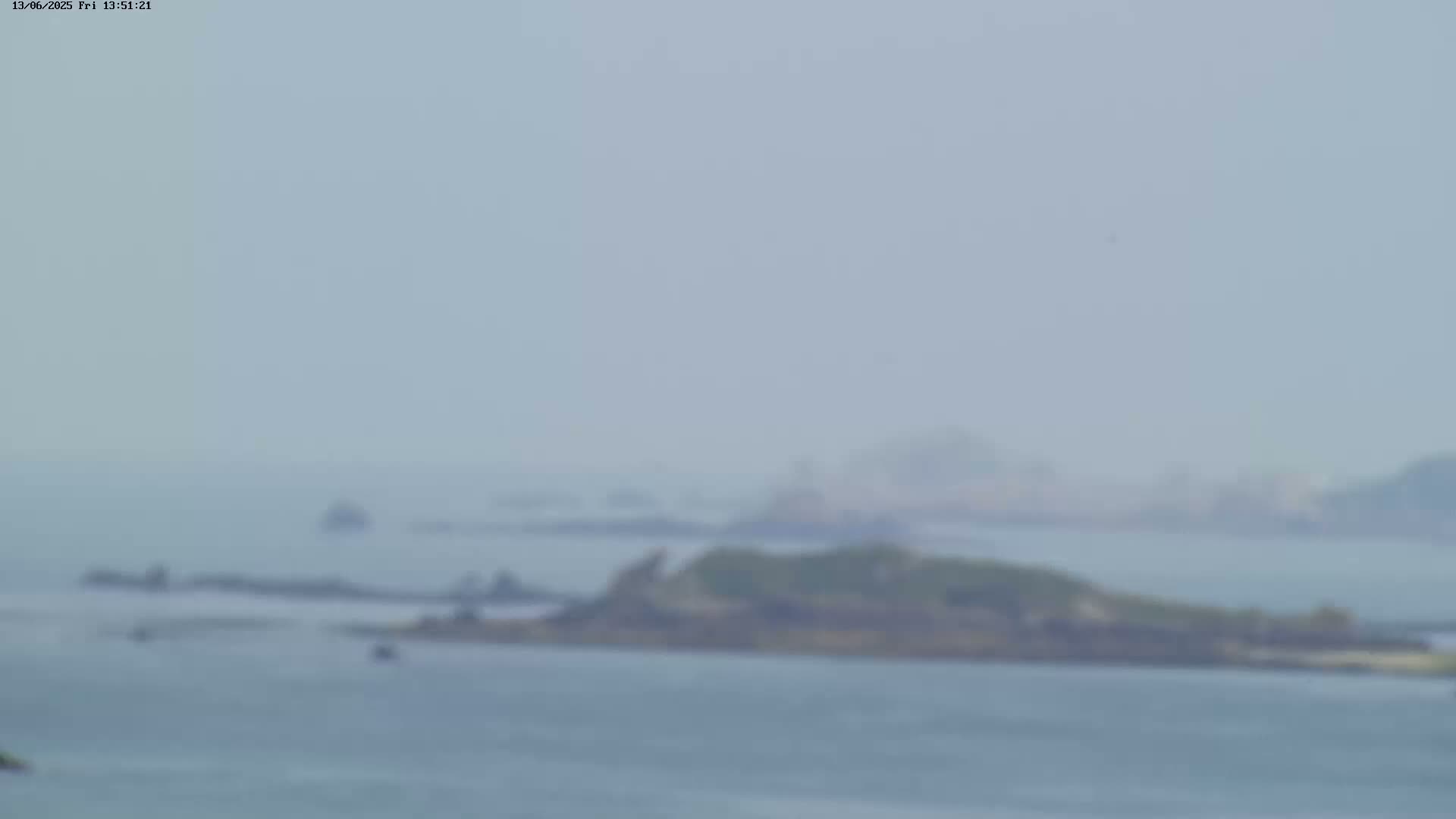 A hazy, distant view shows several small islands and rocky outcrops in a calm body of water.