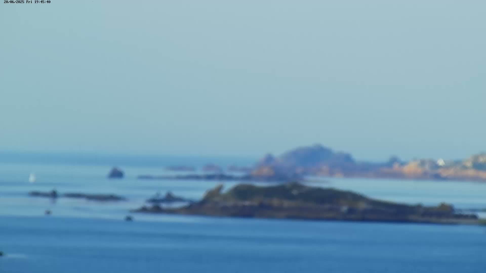 A blurry long shot shows a calm body of water with several small islands and a hazy sky.