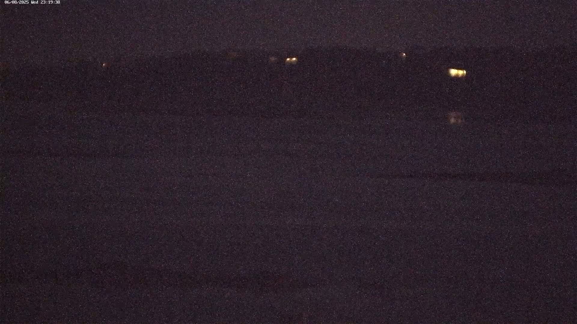 A dark, nighttime scene shows a distant horizon with a few faint lights, and a mostly dark foreground.