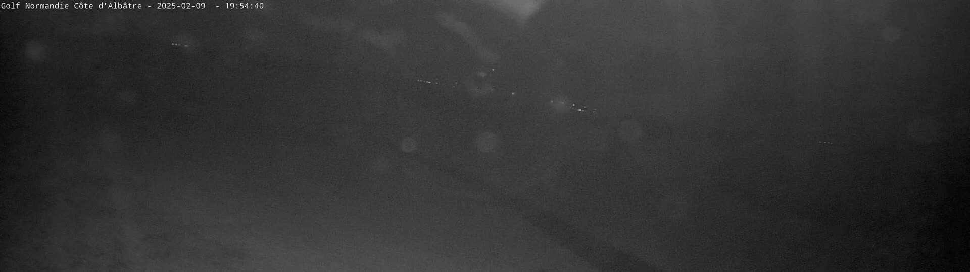 A dark, grainy nighttime image shows a few small, indistinct lights in the distance.