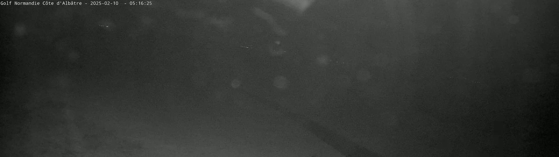 A dark, blurry image shows a nighttime outdoor scene with heavy mist or fog.