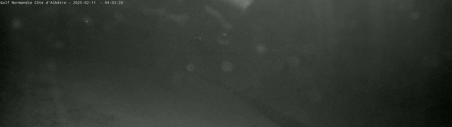 A dark, blurry image shows a nighttime outdoor scene with a few faint lights visible in the distance.