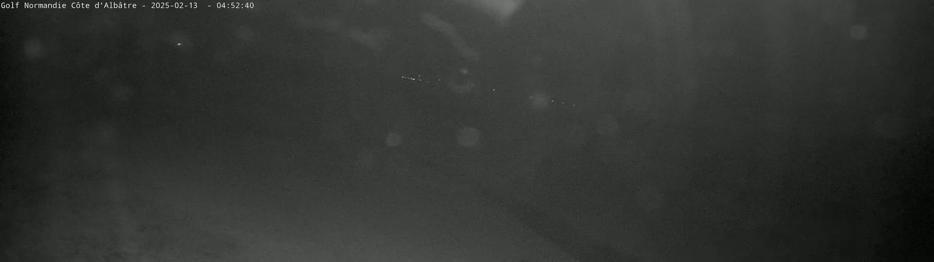 A dark, blurry nighttime outdoor scene shows a few faint lights in the distance.
