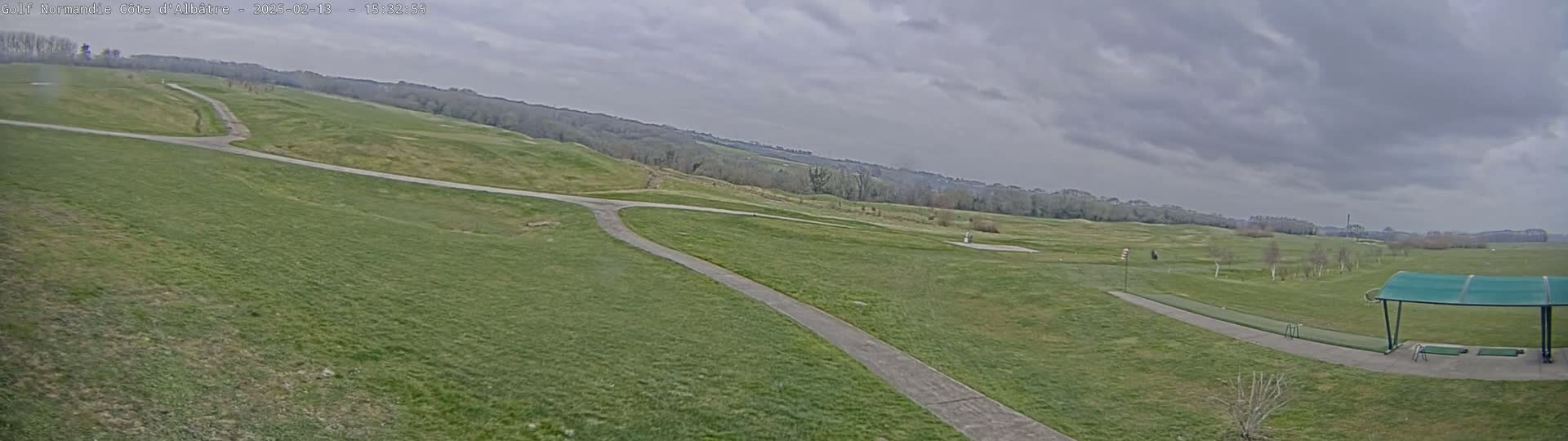 A golf course with a driving range under an overcast sky.
